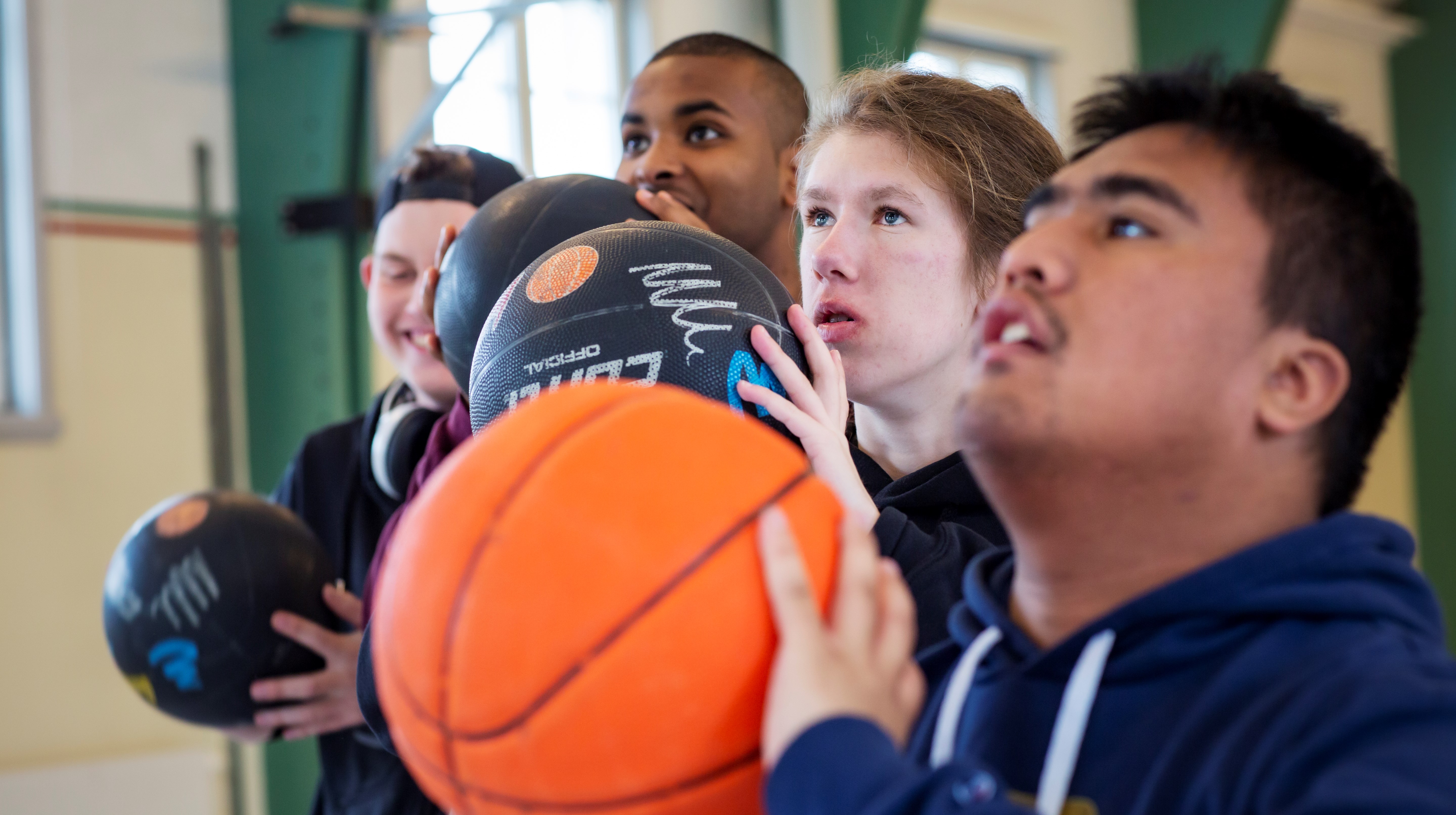 fyra personer står med en basketboll och ska skjuta mot korgen